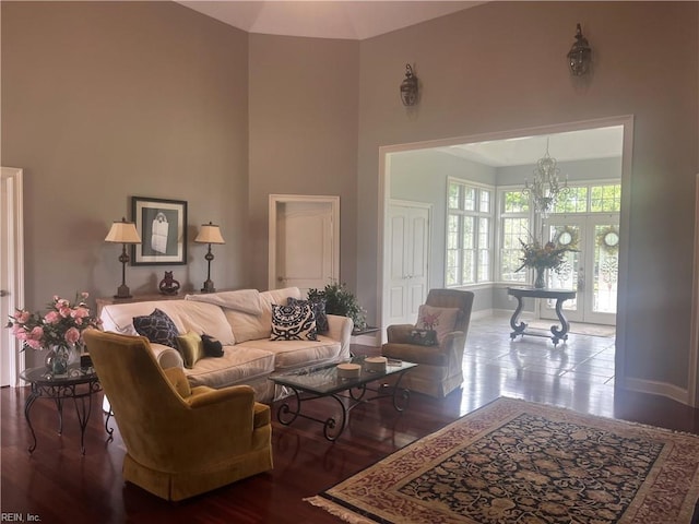 living room with a towering ceiling, an inviting chandelier, and hardwood / wood-style floors