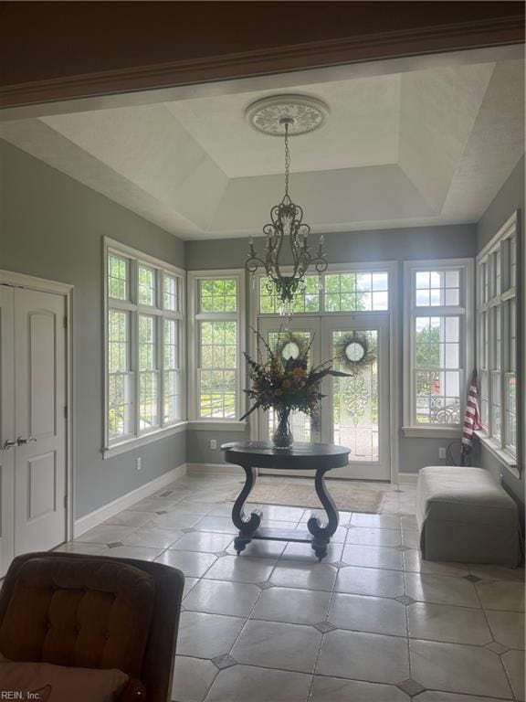 interior space with a tray ceiling, a healthy amount of sunlight, and a notable chandelier