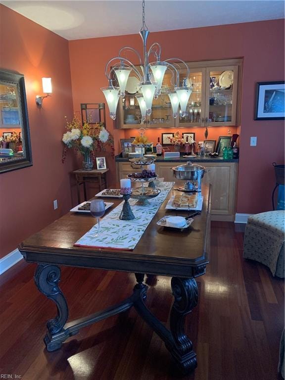 dining area with dark hardwood / wood-style flooring and an inviting chandelier