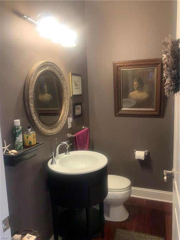 bathroom with hardwood / wood-style flooring, toilet, and vanity