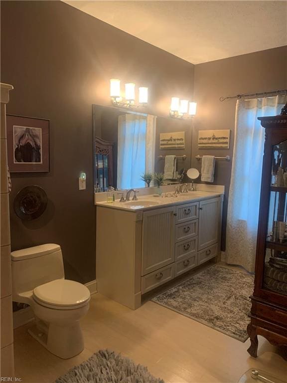 bathroom featuring vanity with extensive cabinet space, dual sinks, toilet, and tile flooring