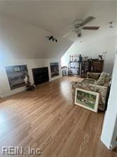 living room with ceiling fan, wood-type flooring, and vaulted ceiling