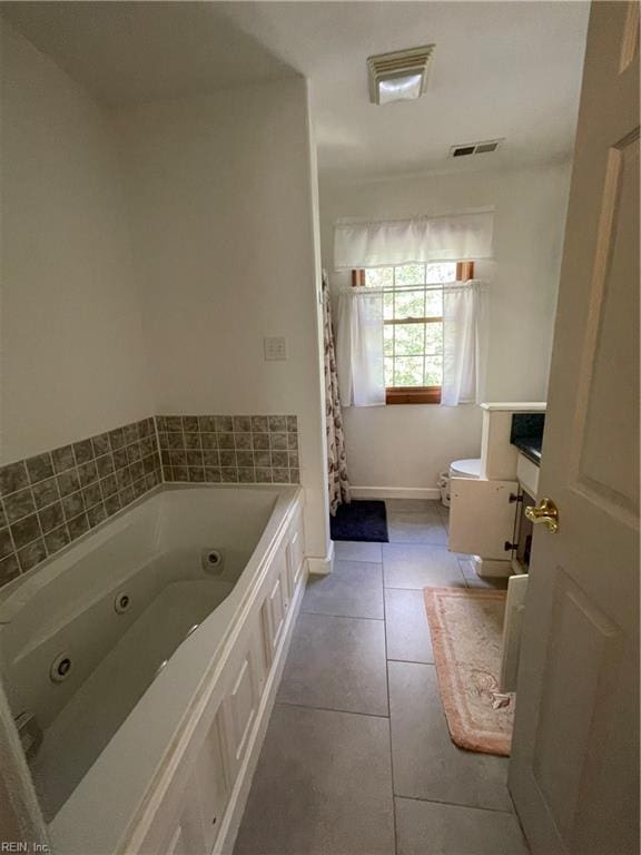 bathroom with a washtub, vanity, tile patterned floors, and toilet