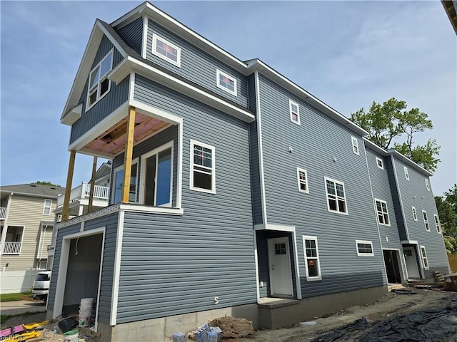 rear view of house featuring a balcony and a garage