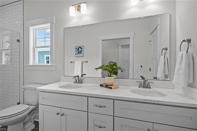 bathroom with a tile shower, vanity, and toilet