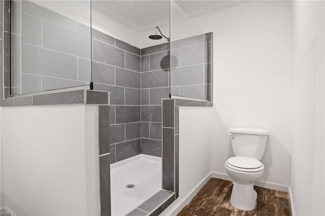 bathroom featuring tiled shower, toilet, and wood-type flooring