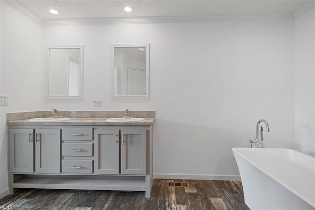 bathroom with dual sinks, vanity with extensive cabinet space, a textured ceiling, ornamental molding, and hardwood / wood-style flooring