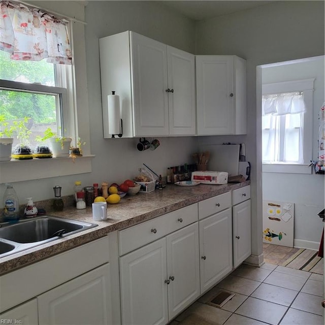 kitchen with sink, white cabinetry, and light tile flooring