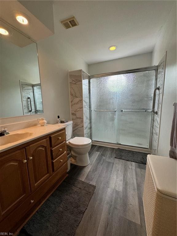 bathroom with hardwood / wood-style floors, vanity, toilet, and an enclosed shower