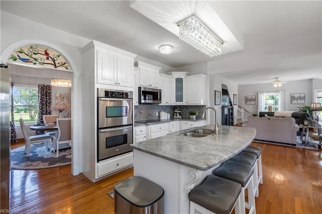 kitchen with white cabinets, sink, a breakfast bar area, tasteful backsplash, and stainless steel appliances