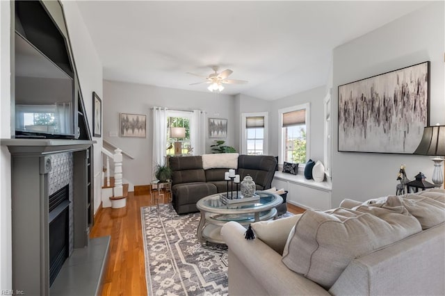 living room featuring a tile fireplace, ceiling fan, and light hardwood / wood-style floors