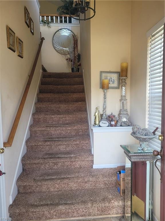 stairway with a notable chandelier and carpet