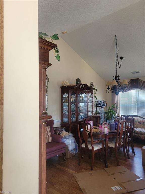 dining space with lofted ceiling, an inviting chandelier, and hardwood / wood-style floors