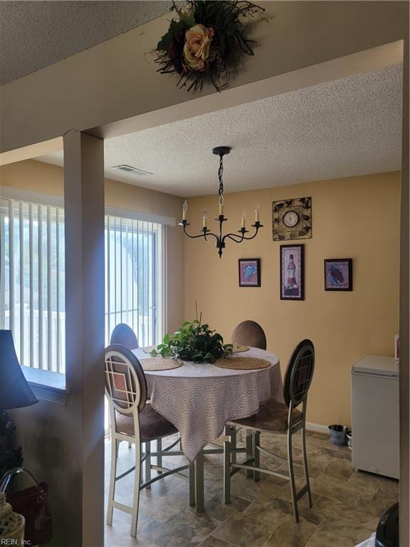 tiled dining room with a textured ceiling and an inviting chandelier