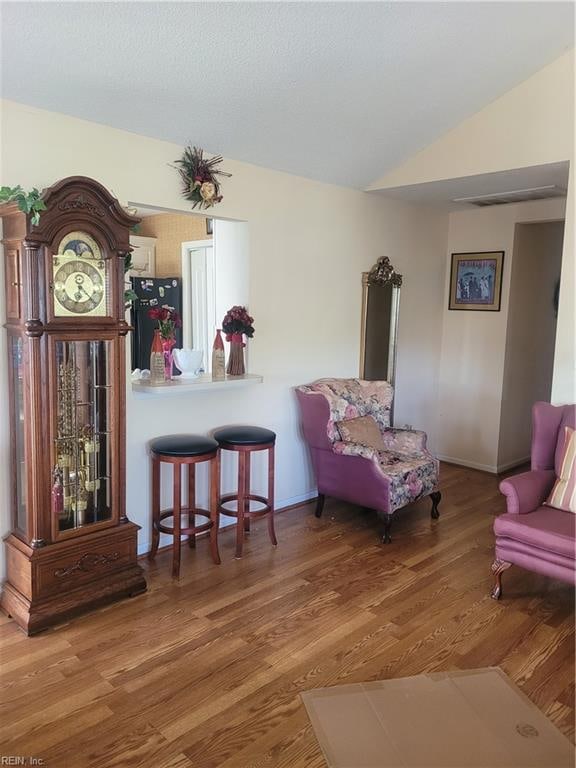 sitting room featuring vaulted ceiling and hardwood / wood-style floors