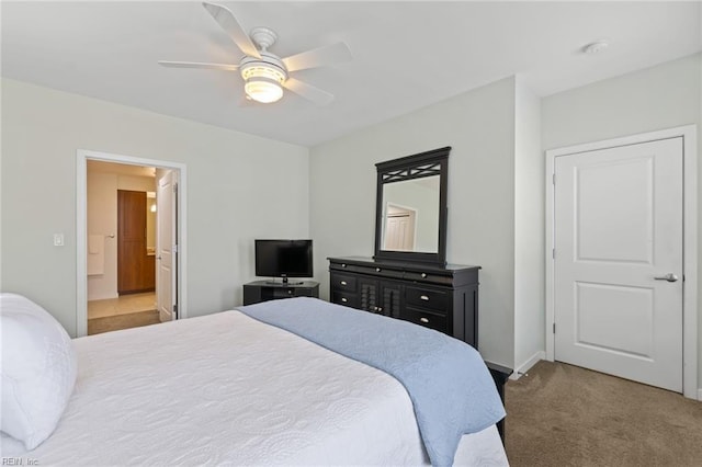 bedroom with ceiling fan, ensuite bathroom, and carpet flooring