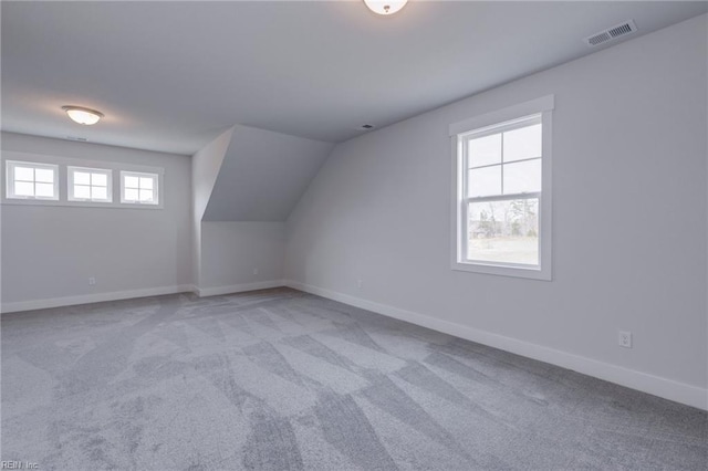 additional living space featuring plenty of natural light, light colored carpet, and vaulted ceiling