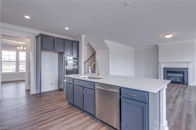 kitchen featuring crown molding, sink, an island with sink, appliances with stainless steel finishes, and light hardwood / wood-style floors