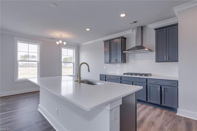 kitchen featuring a center island with sink, stainless steel gas cooktop, wall chimney exhaust hood, and sink