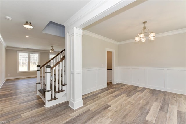 interior space with ceiling fan with notable chandelier, light hardwood / wood-style floors, ornate columns, and crown molding