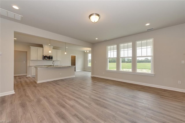 unfurnished living room featuring sink and light wood-type flooring