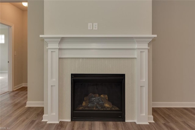 interior details featuring a tile fireplace and wood-type flooring