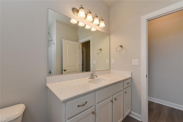 bathroom with toilet, vanity, and hardwood / wood-style flooring