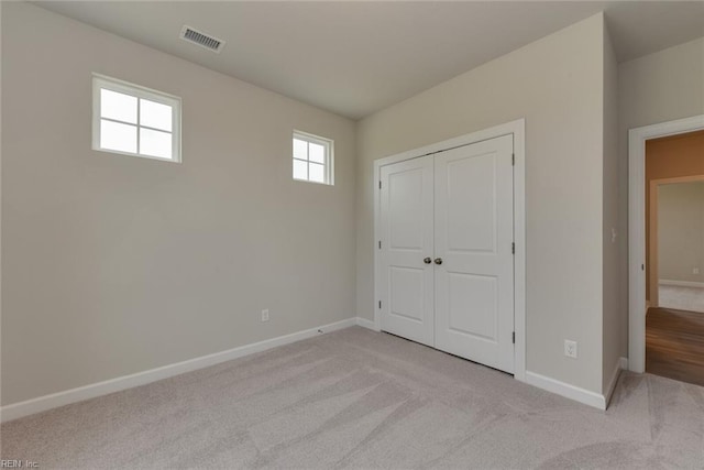 unfurnished bedroom with light carpet and a closet