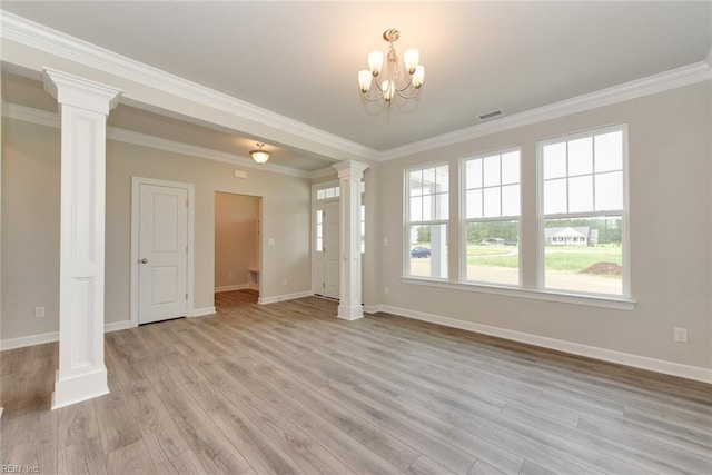 spare room featuring light hardwood / wood-style floors, ornate columns, crown molding, and a notable chandelier