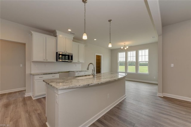 kitchen featuring sink, light hardwood / wood-style flooring, white cabinets, and pendant lighting