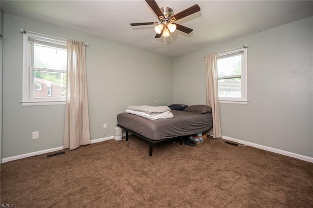 carpeted bedroom featuring multiple windows and ceiling fan