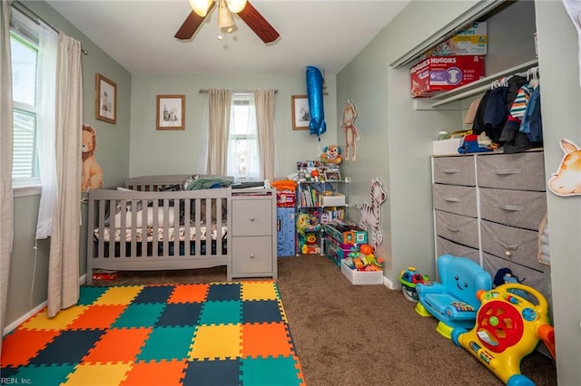 carpeted bedroom featuring ceiling fan and a nursery area