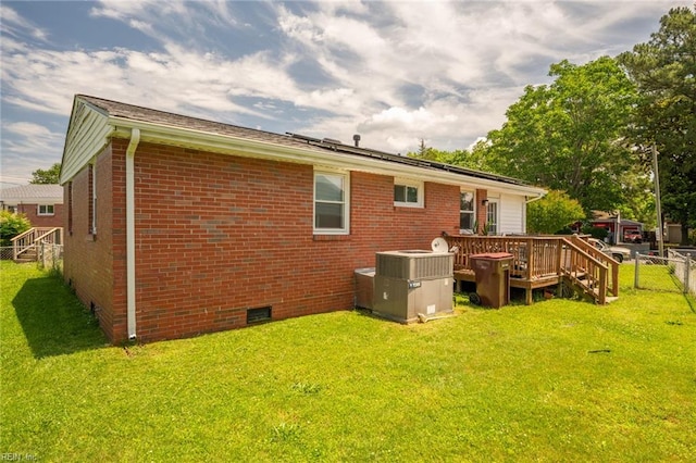 rear view of property featuring a deck, a yard, and central AC