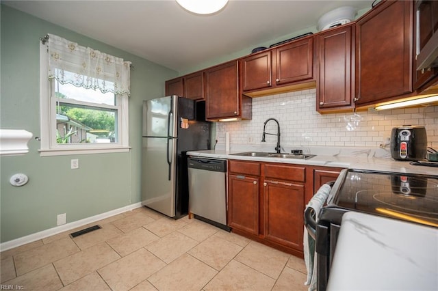 kitchen with light stone countertops, sink, backsplash, light tile patterned floors, and appliances with stainless steel finishes