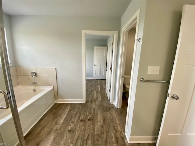 bathroom featuring a bath, toilet, and wood-type flooring