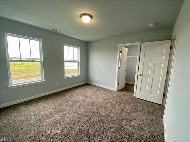 unfurnished bedroom featuring carpet, a closet, and a walk in closet