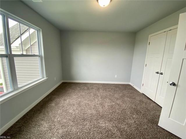 unfurnished bedroom featuring dark carpet and a closet