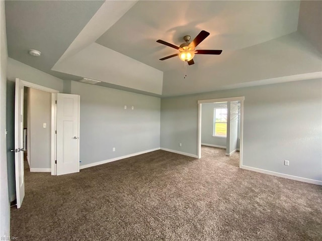 carpeted empty room featuring ceiling fan and a raised ceiling