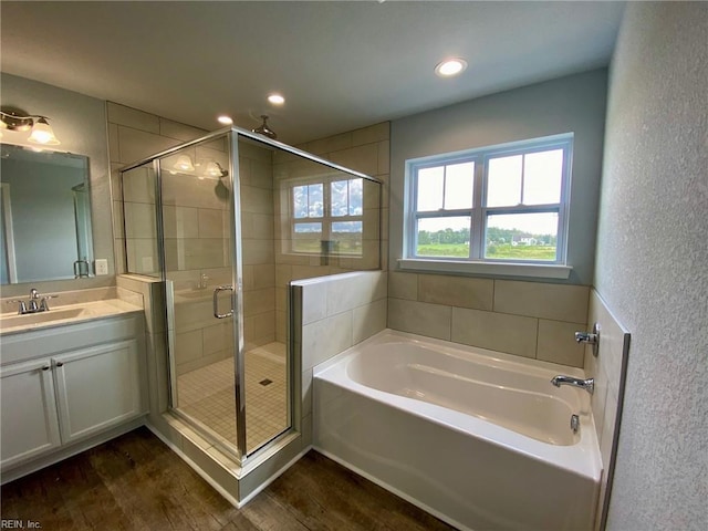 bathroom with wood-type flooring, vanity, and plus walk in shower