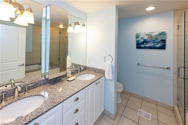 bathroom featuring tile flooring, double sink, vanity with extensive cabinet space, a shower with door, and toilet