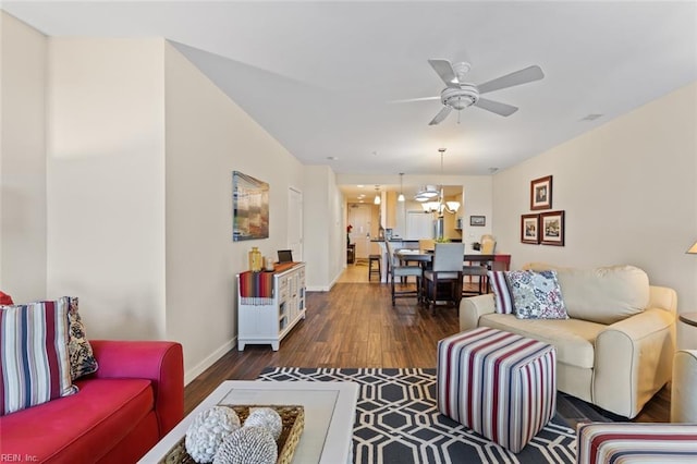 living room with dark wood-type flooring and ceiling fan with notable chandelier