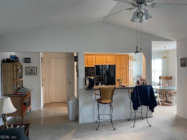 kitchen featuring light brown cabinetry, black fridge, ceiling fan, light colored carpet, and high vaulted ceiling