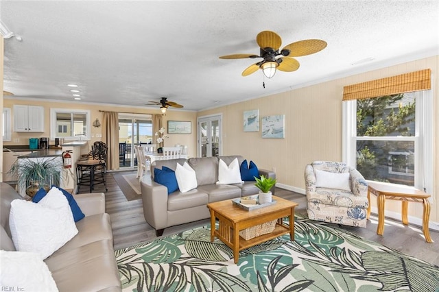 living room featuring a textured ceiling, light hardwood / wood-style floors, ceiling fan, and ornamental molding