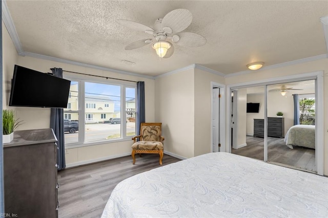 bedroom featuring ceiling fan, light hardwood / wood-style flooring, a textured ceiling, a closet, and ornamental molding