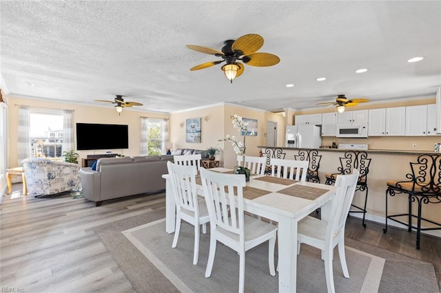 dining area featuring crown molding, a textured ceiling, and light wood-type flooring