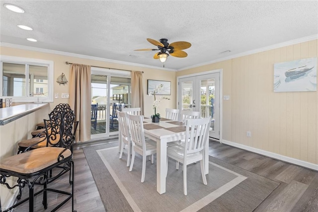 dining area with french doors, dark hardwood / wood-style flooring, ornamental molding, a textured ceiling, and ceiling fan