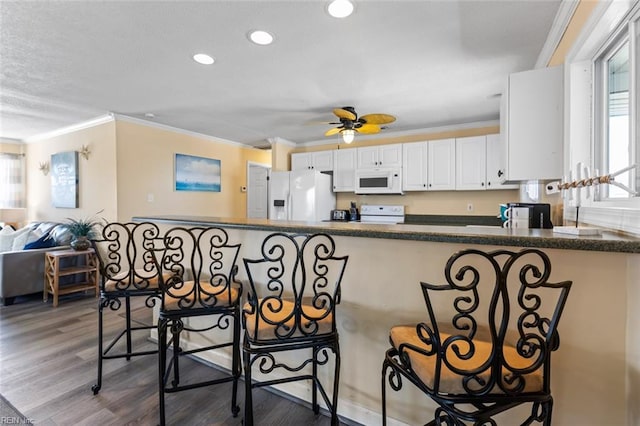 kitchen featuring white appliances, white cabinets, crown molding, ceiling fan, and dark hardwood / wood-style flooring