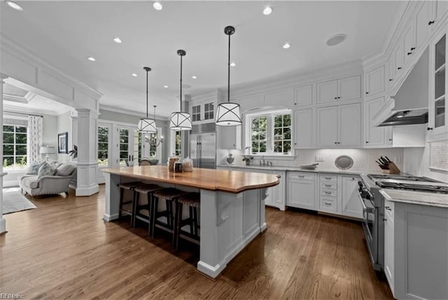 kitchen featuring premium appliances, a center island, white cabinetry, and a wealth of natural light