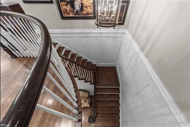 stairs featuring hardwood / wood-style floors and a notable chandelier