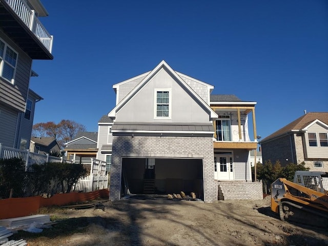 view of front facade featuring a garage, metal roof, a standing seam roof, fence, and brick siding